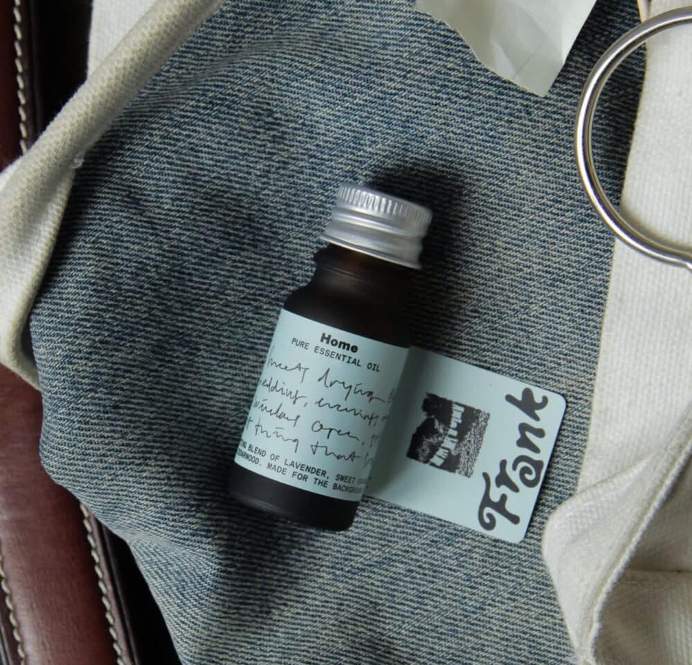 A bottle of Frank pure essential oil on denim fabric next to a Frank card